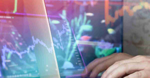 Mano soltando monedas frente a gráfico bursátil simbolizando el primer paso hacia invertir en ETF.