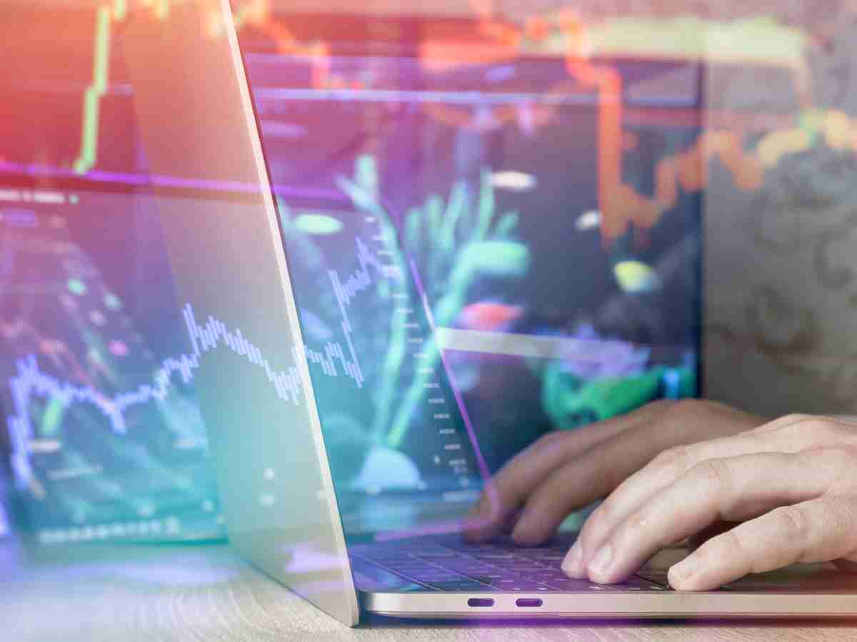Mano soltando monedas frente a gráfico bursátil simbolizando el primer paso hacia invertir en ETF.